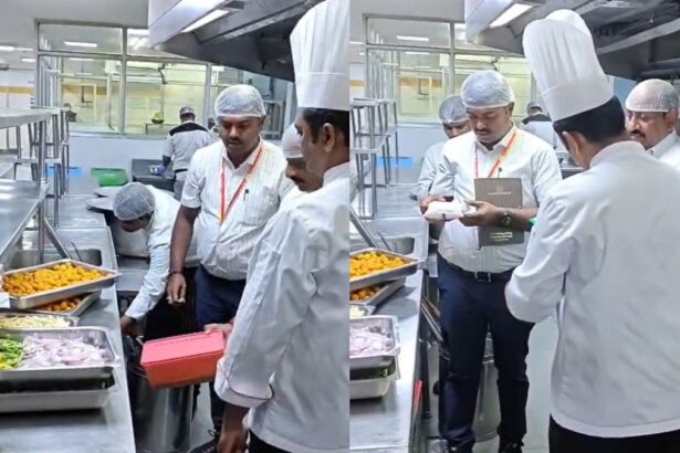 Team of chefs in white uniforms and hairnets inspect trays of food on a stainless steel prep line in a commercial kitchen
