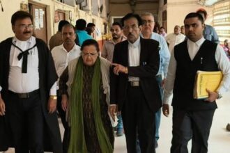 A group of formally dressed people walking down a hallway, led by a woman in green scarf, flanked by men in suits.